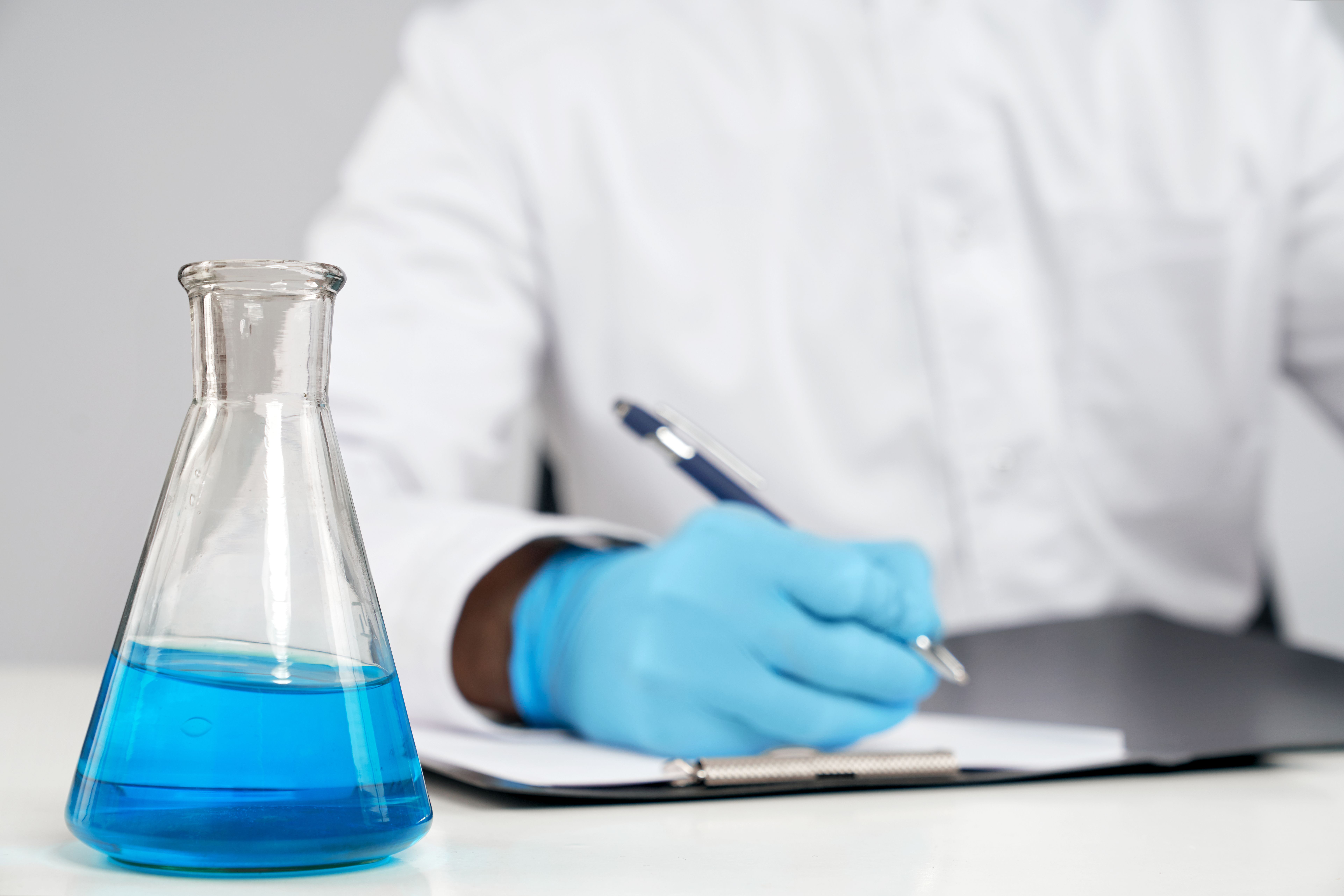 chemist-writing-report-flask-nearby.jpg